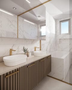 Banheiro planejado com bancada dupla, cuba de apoio, marcenaria ripada amadeirada e metais dourados, revestimento em mármore e iluminação embutida.